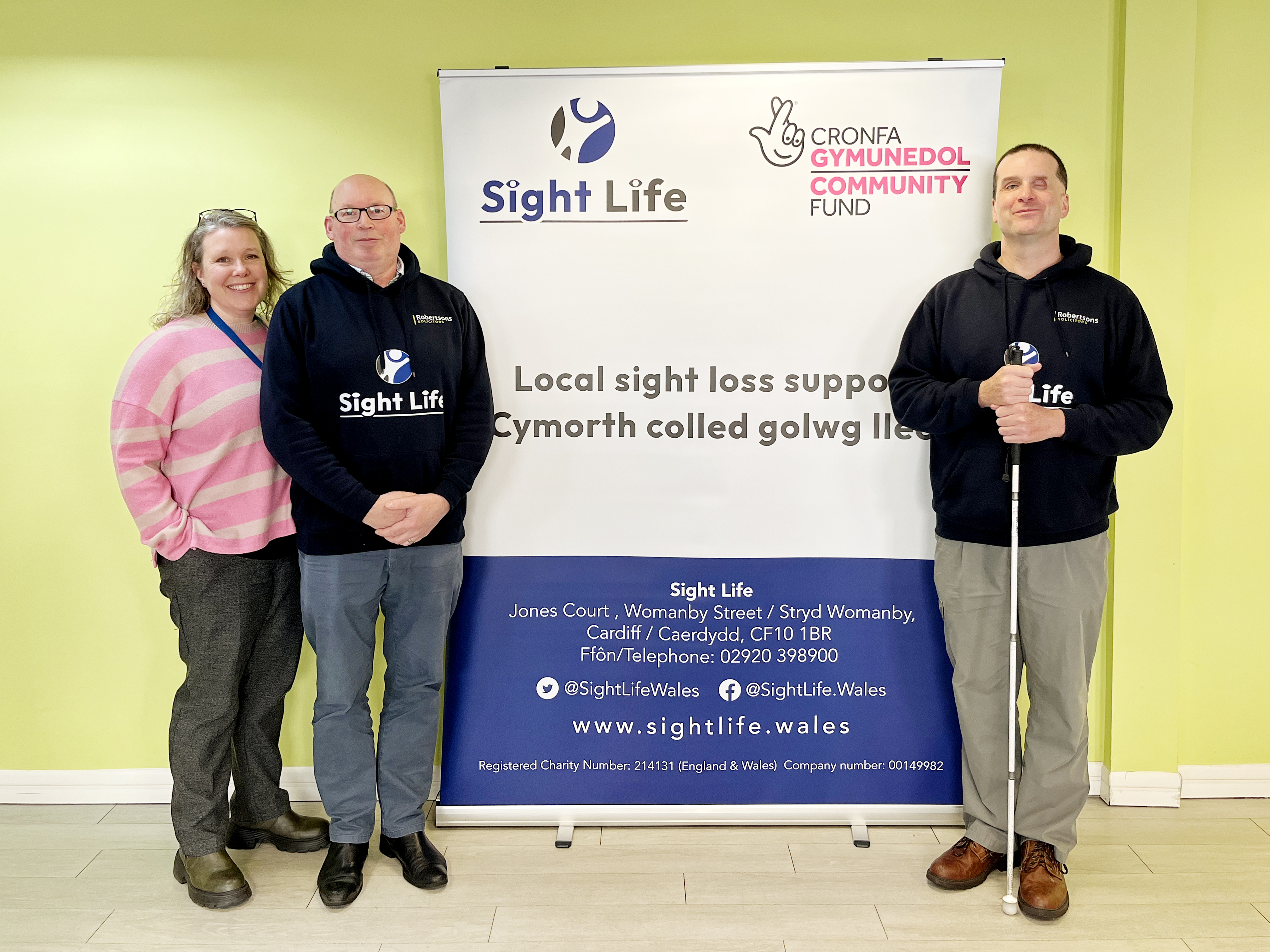 Hazel, Dylan and Stuart standing by a Sightlife pull up banner.