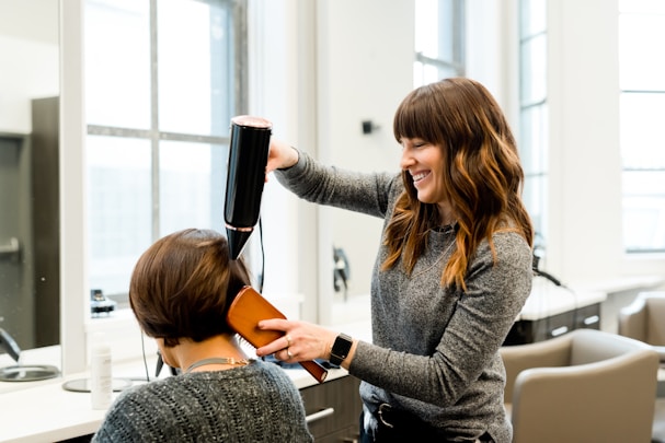 Women blowdrying hair of customer