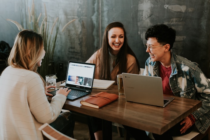students at table on laptops in conversation