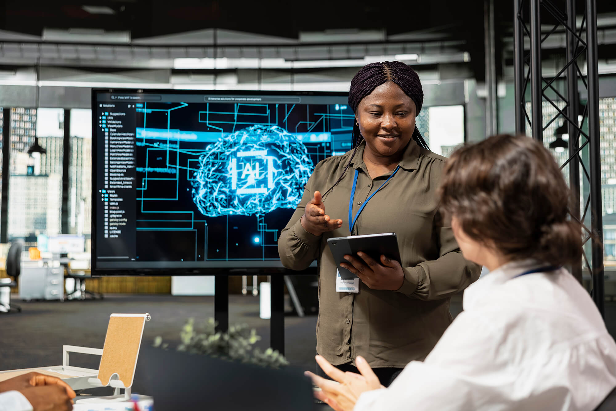 A woman presents an AI technology concept on a large digital screen to colleagues during a meeting in a modern office.